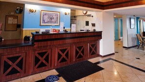 A hotel reception area with a star-shaped floor design, a wooden reception desk, and a chandelier. - Garnet Inn & Suites, Orlando (Orlando)
