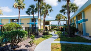 A hotel with a central courtyard, palm trees, and a pathway leading to the building. - Garnet Inn & Suites, Orlando (Orlando)