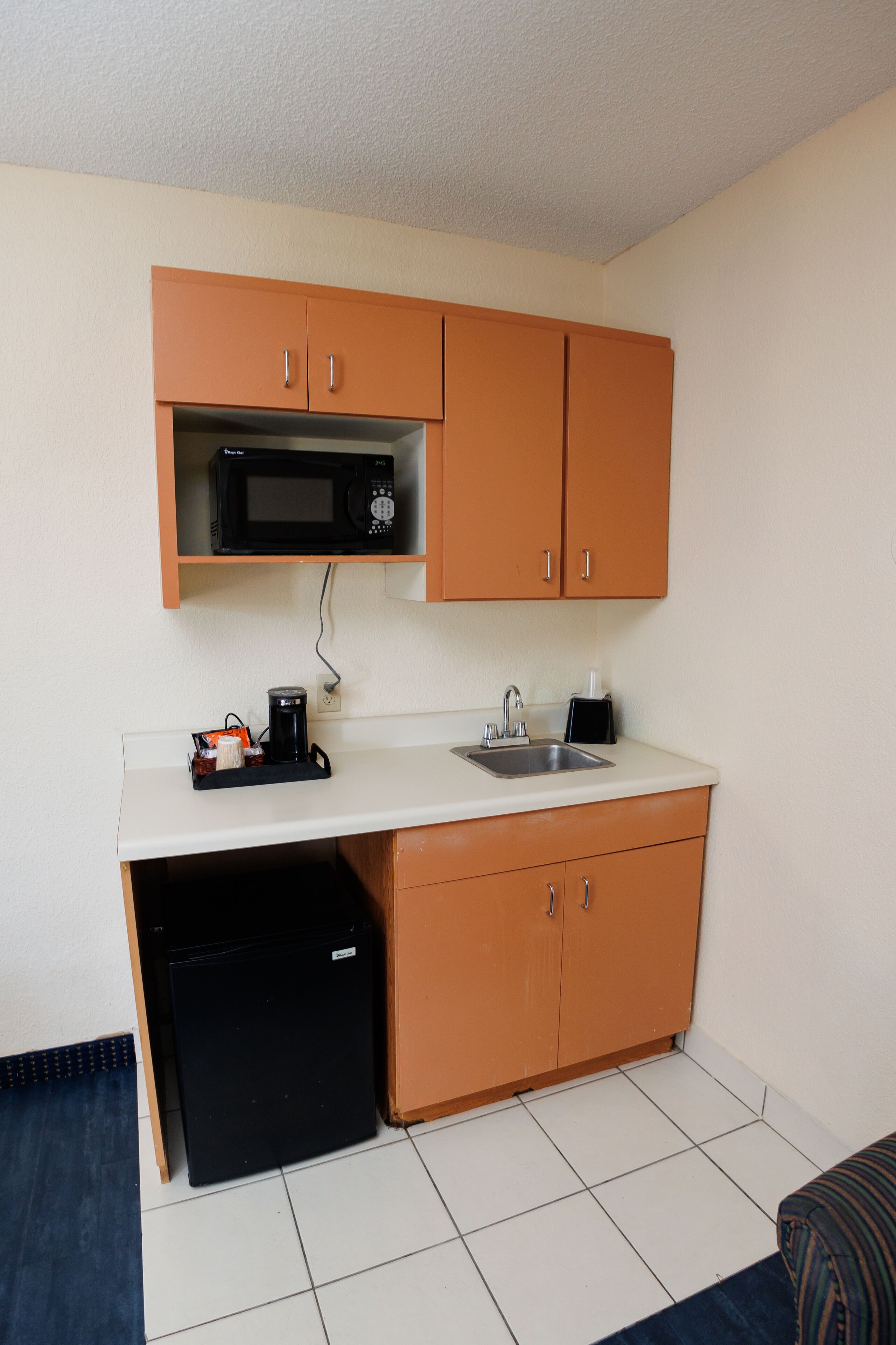 A compact kitchenette with a microwave, coffee maker, and sink.