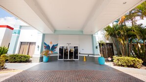 A hotel entrance with a tiled walkway, a large potted plant, and a mural on the wall. - Garnet Inn & Suites, Orlando (Orlando)