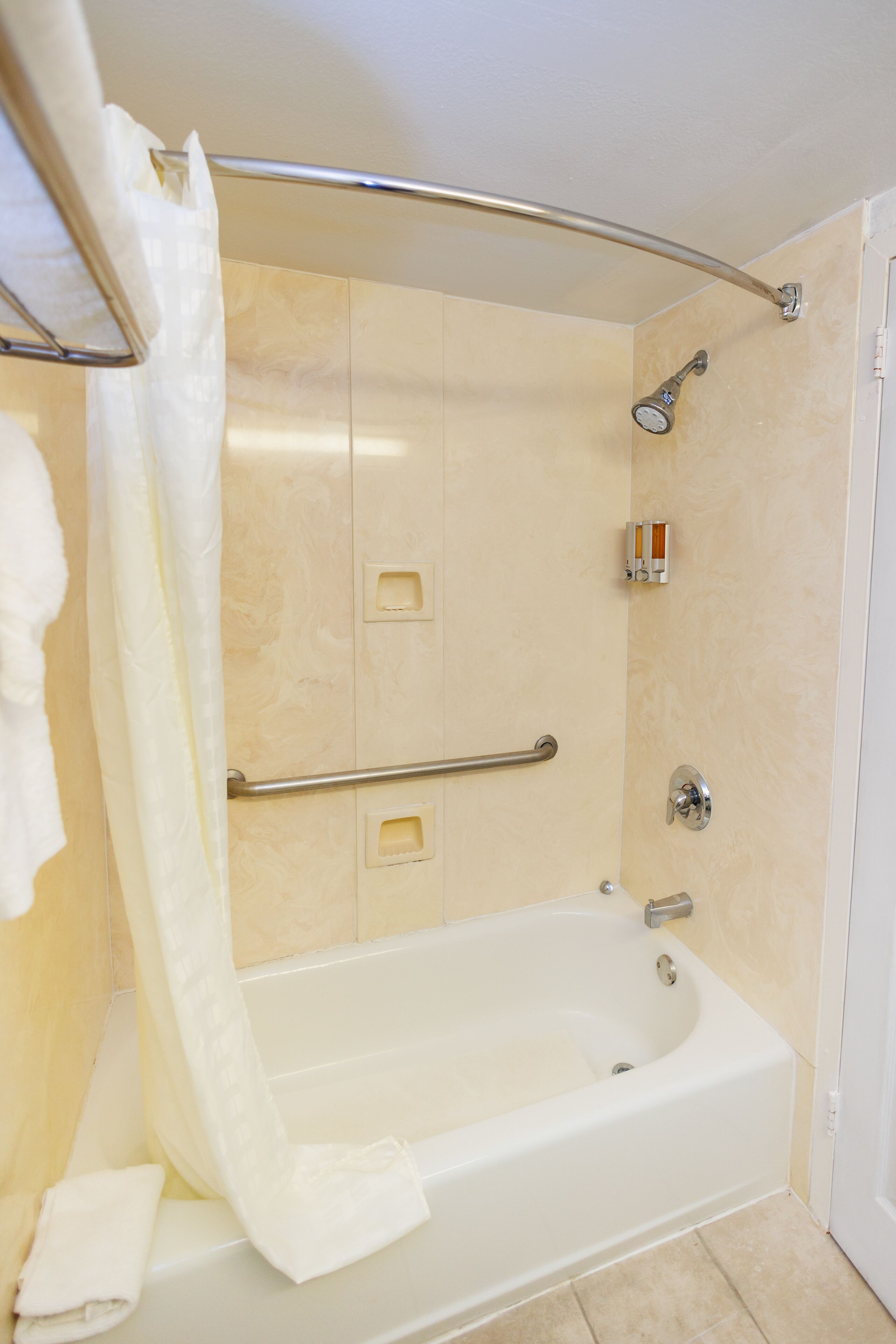 A modern bathroom with a bathtub, shower, and handrails.