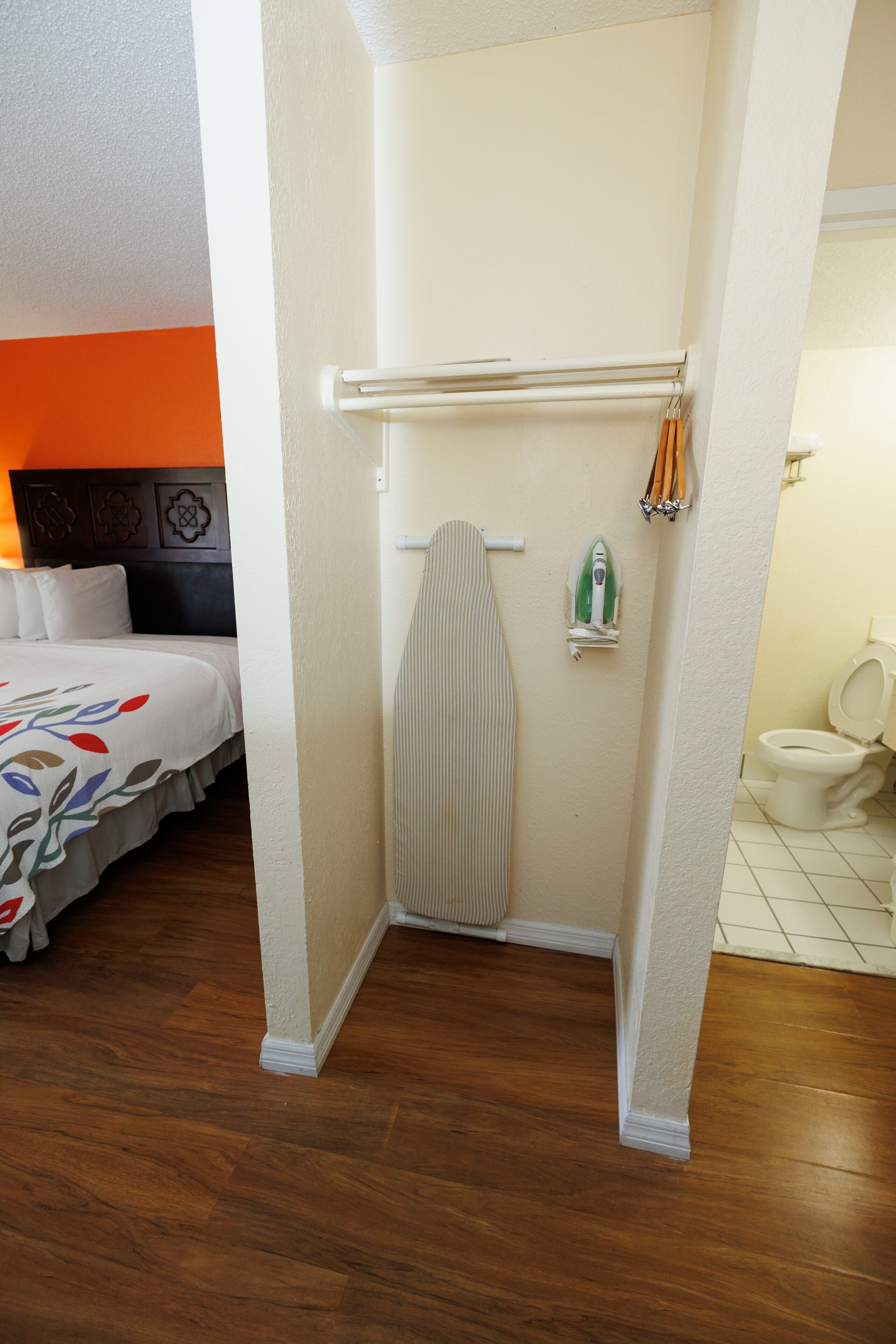 A hotel room with a bed, a shower area, and a toilet.