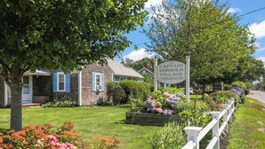 A sign for Captal Gosnold Village Condominiums, surrounded by well-maintained lawns and a white picket fence.