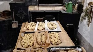 Una cocina con horno de leña, bandejas para hornear y un regador verde.