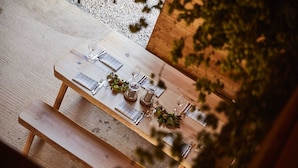 Una mesa de madera al aire libre con un banco, rodeada de follaje.