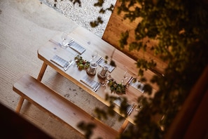 A wooden table set outdoors with a bench, surrounded by greenery. - Ferienwohnung Schusterstube - Ferienhof Stephanus (Ebermannstadt)
