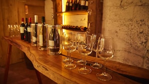 Una barra de madera con botellas de vino y copas.