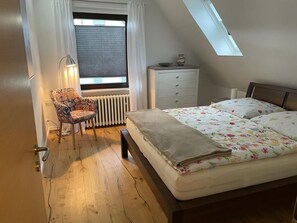 Makuuhuoneessa on sänky, tuoli, lipasto, patteri ja kattovalokuvio.