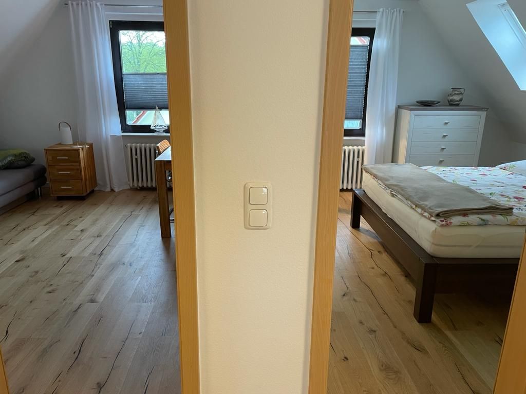 A room with a bed, a dresser, a radiator, and a window with curtains.