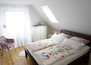 A bedroom with a bed, a chair, a dresser, and a skylight. - Hänsel Vacation Rental, Germany (Zinnowitz)