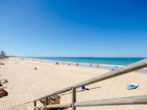 A beach with a wooden boardwalk leading to the shore, clear blue sky, and calm sea. - Semi detached house in El Manantial (El Puerto de Santa María)