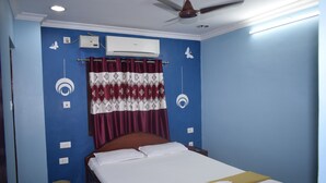 Un dormitorio con cama, aire acondicionado, ventilador de techo y cortina.