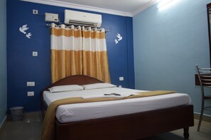 A bedroom with a bed, a chair, and an air conditioning unit on the wall. - Golden Sun Inn (Puducherry)