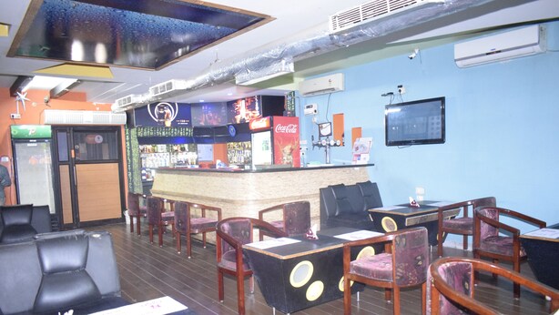 Un restaurante con barra, mesas y una pantalla de televisión.
