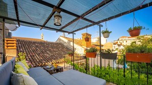 A balcony with a cushioned seating area, hanging planters, and a view of the cityscape. - Apartment Igor is located in Pula, 100 m from the Pula Arena. (Pula)