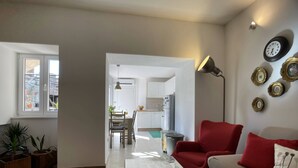 A living room with a sofa, a coffee table, and a red armchair. There is a dining area in the background with a table and chairs. - Apartment Igor is located in Pula, 100 m from the Pula Arena. (Pula)