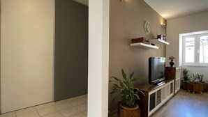 A modern living room with a flat-screen TV, wooden cabinets, a potted plant, and a large window. - Apartment Igor is located in Pula, 100 m from the Pula Arena. (Pula)