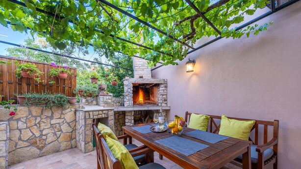 An outdoor patio with a stone fireplace, wooden table, and chairs. - Apartment Igor is located in Pula, 100 m from the Pula Arena. (Pula)