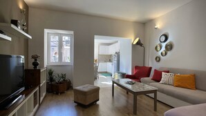 A modern living room with a flat-screen TV, a sofa with cushions, a coffee table, and a dining area visible through a window. - Apartment Igor is located in Pula, 100 m from the Pula Arena. (Pula)