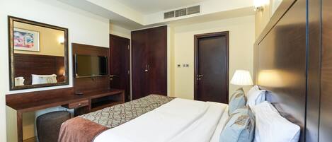 Ein Hotelzimmer mit Bett, Schreibtisch, Spiegel, Kleiderschrank und Fernseher.