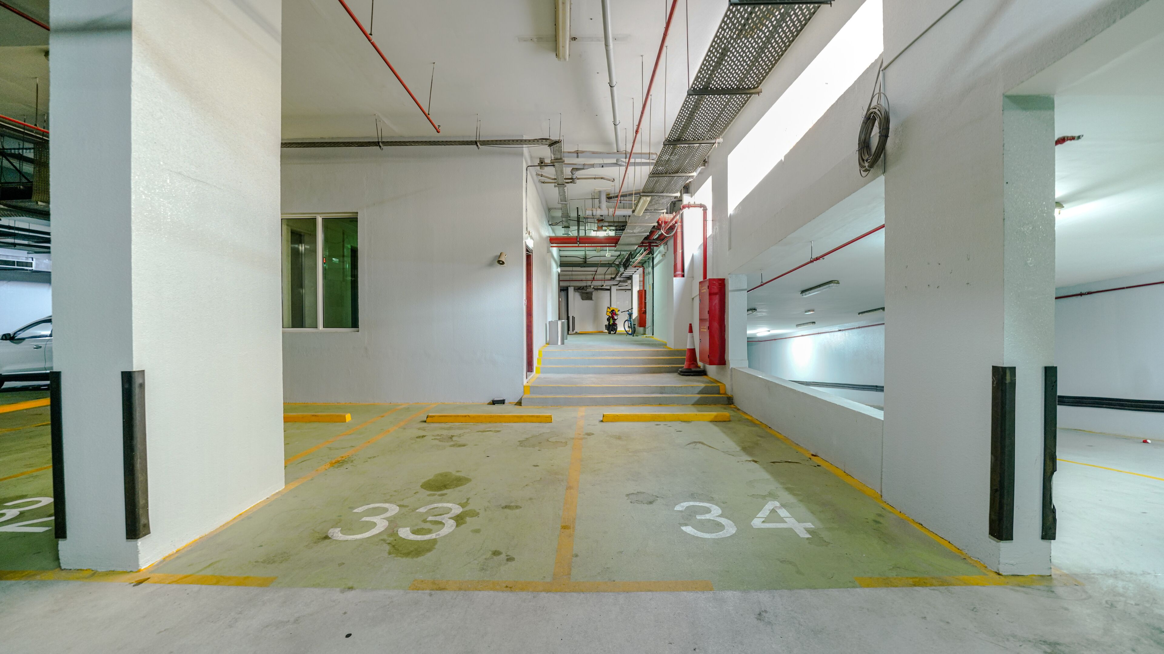 Un garaje de estacionamiento limpio y bien iluminado, con espacios claramente delimitados y una escalera central que conduce a niveles superiores.