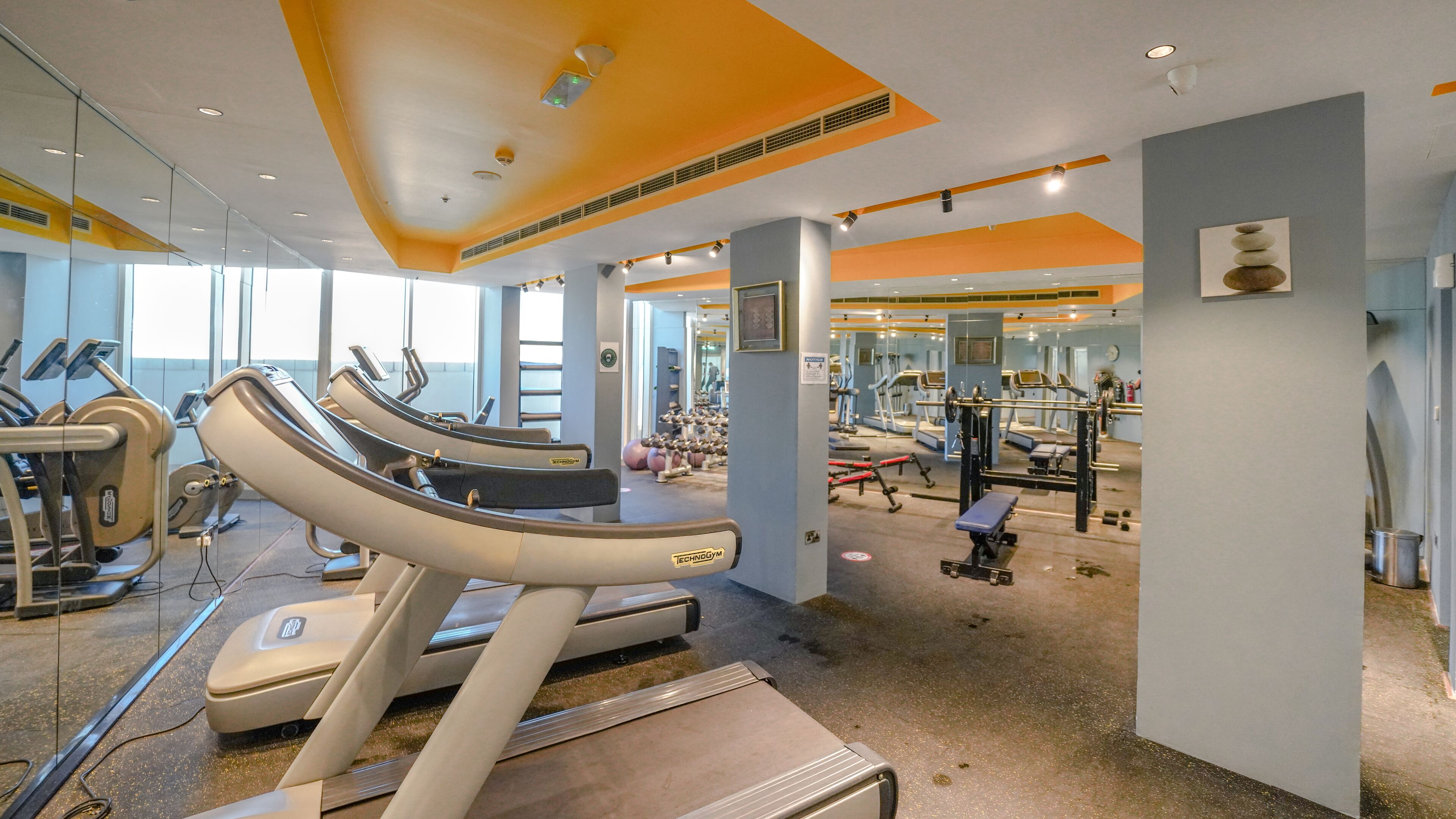 Ein Fitnessstudio mit Laufbändern, Kraftgeräten und Spiegeln.