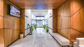 A modern lobby with wooden paneling, marble flooring, and a television mounted on the wall. - City Stay Residences (Dubai)