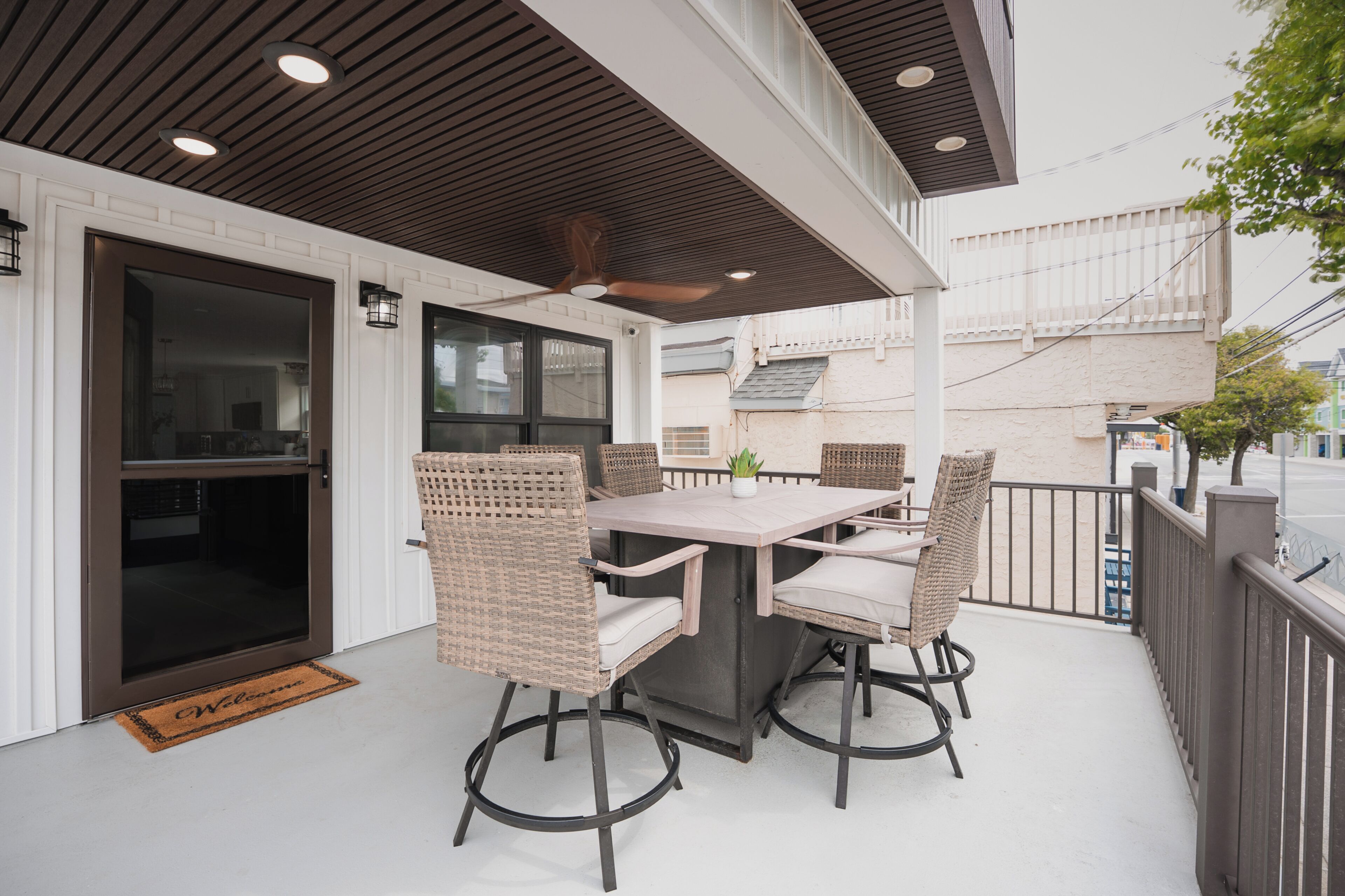 A covered outdoor patio with a table and chairs, a ceiling fan, and a door leading to an interior space.