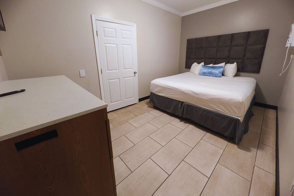 A bedroom with a bed, a dresser, and a door.