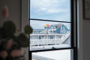 Vista a través de una ventana que muestra un edificio con balcón y una estructura colorida al fondo.