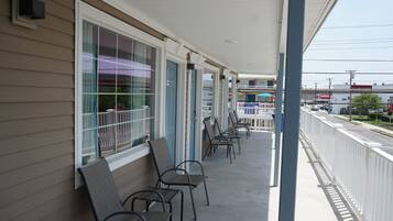 A covered outdoor seating area with rows of chairs and a railing.