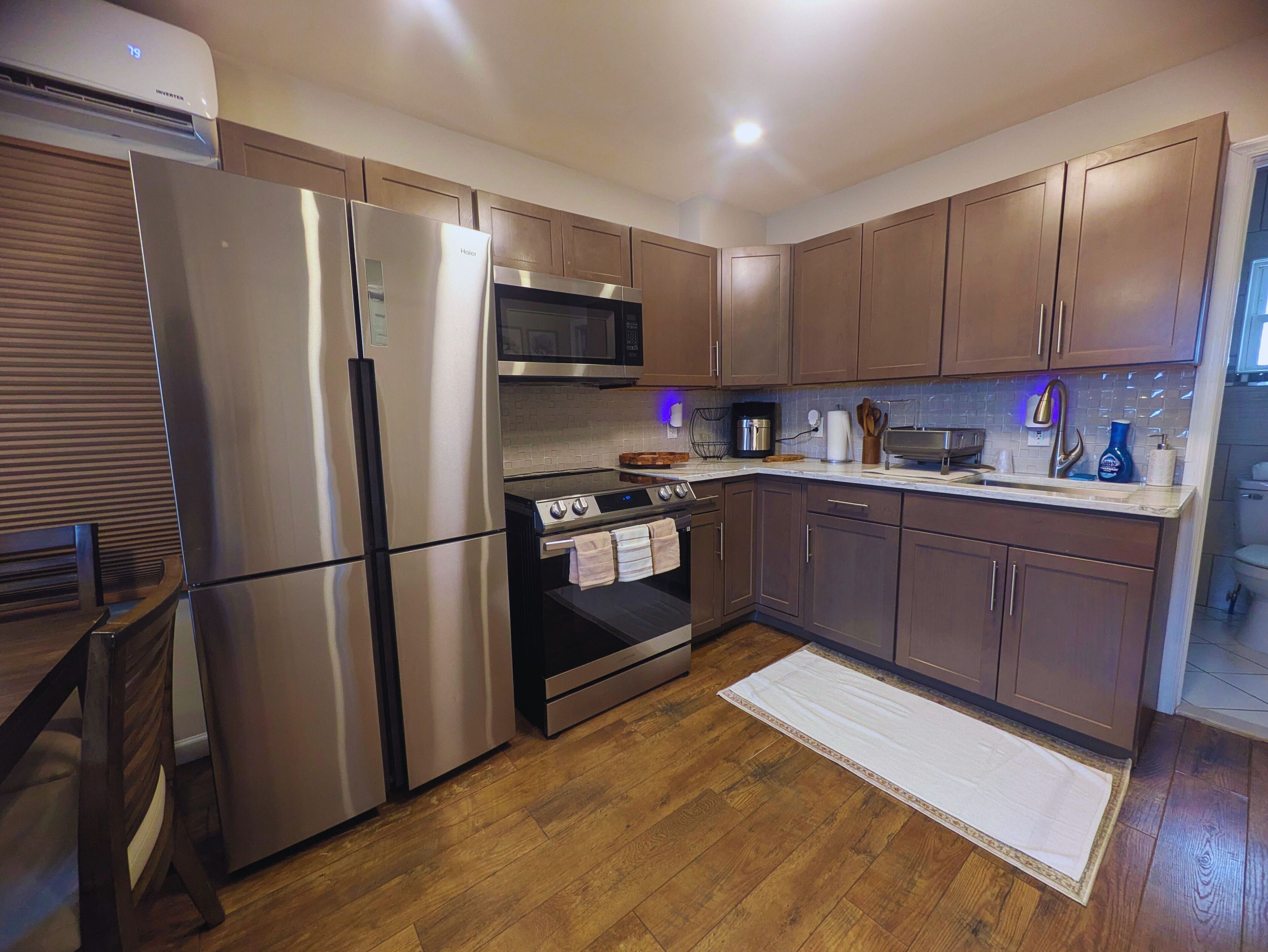 A modern kitchen with stainless steel appliances, wooden cabinets, and a tiled backsplash.
