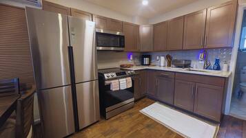 A modern kitchen with stainless steel appliances, wooden cabinets, and a tiled backsplash.