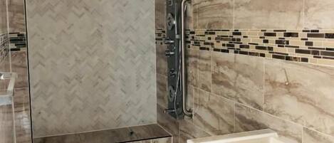 Un baño moderno con ducha, lavamanos y pared con diseño en patrón de espiga.