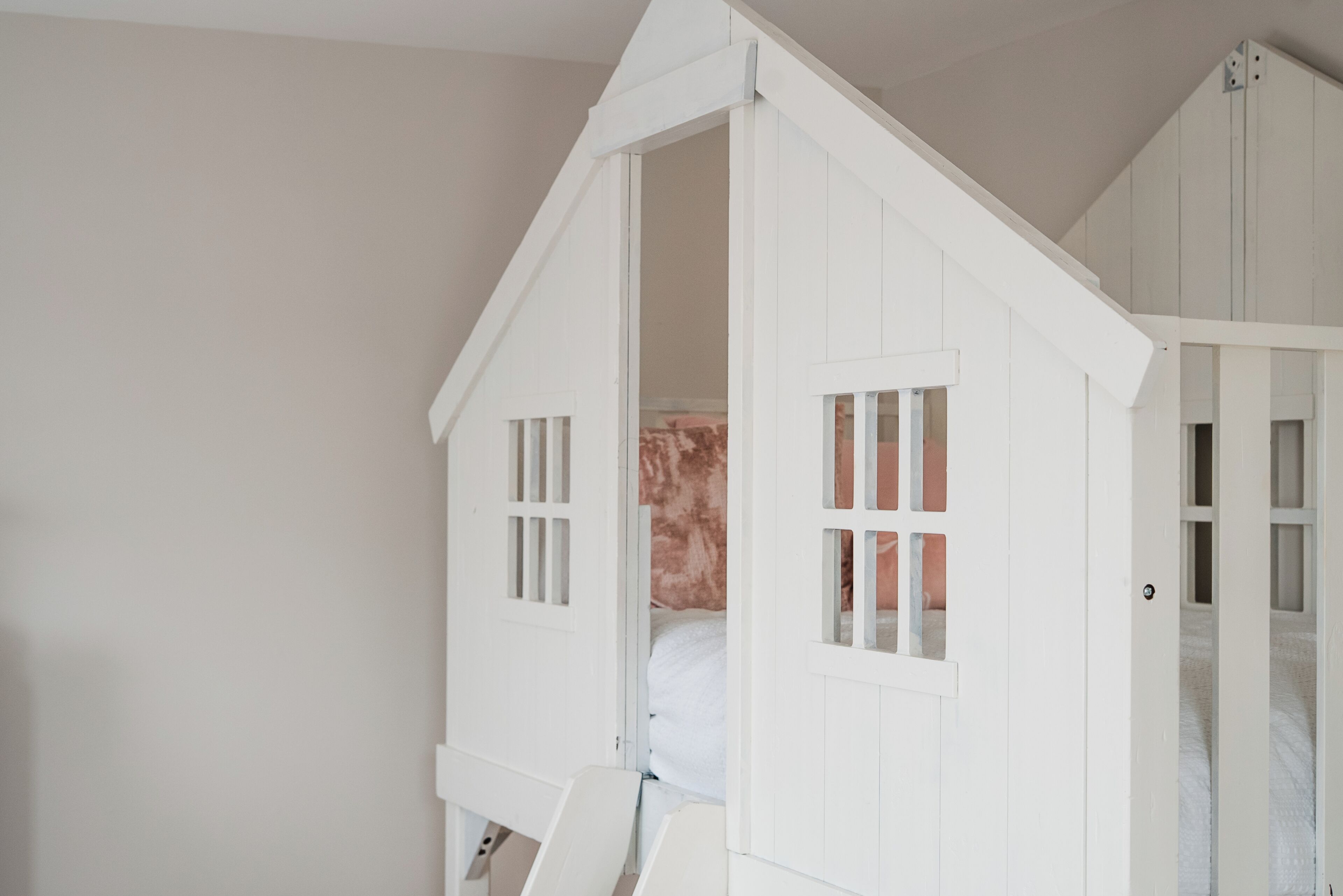 Una habitación con una cama nido, una puerta blanca y una pared blanca.
