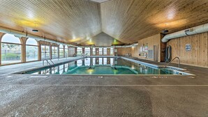 An indoor swimming pool with a wooden ceiling and large windows.