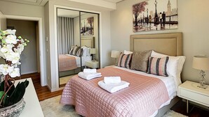 A hotel room with a large bed, a mirror, a painting of a cityscape, and a potted orchid. - Paradise Apartment by LovelyStay (Funchal)