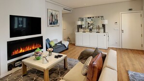 A modern living room with a fireplace, a flat-screen TV, a sofa, and a cabinet with decorative items. - Paradise Apartment by LovelyStay (Funchal)