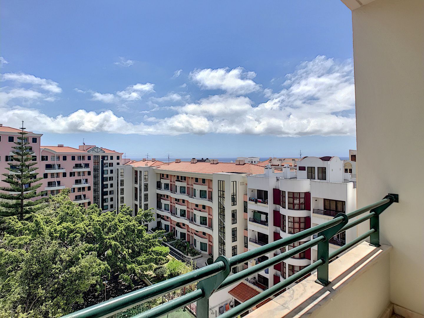 Un quartier résidentiel avec des immeubles à plusieurs étages, des balcons et un ciel dégagé parsemé de nuages.