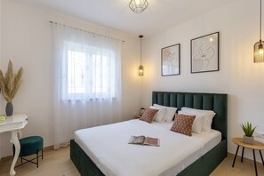 Une chambre bien rangée, avec un lit, une table de chevet et un petit bureau avec une chaise.