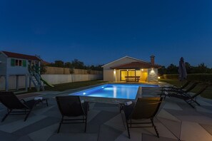 Une piscine avec des chaises longues et une petite maison dotée d’un patio.