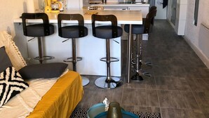 Une cuisine moderne dotée d’un îlot central, de tabourets de bar et d’un coin repas avec un canapé et des coussins.