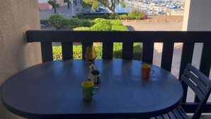 Un balcon avec une table et des chaises, donnant sur une marina où sont amarrés des bateaux.