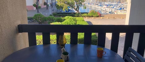 En balkong med ett bord och stolar, med utsikt över en småbåtshamn.