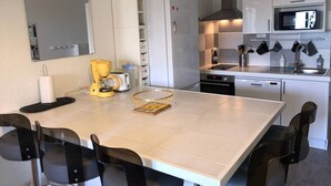 Une cuisine moderne avec des meubles blancs, un four à micro-ondes, une cuisinière et une machine à café.