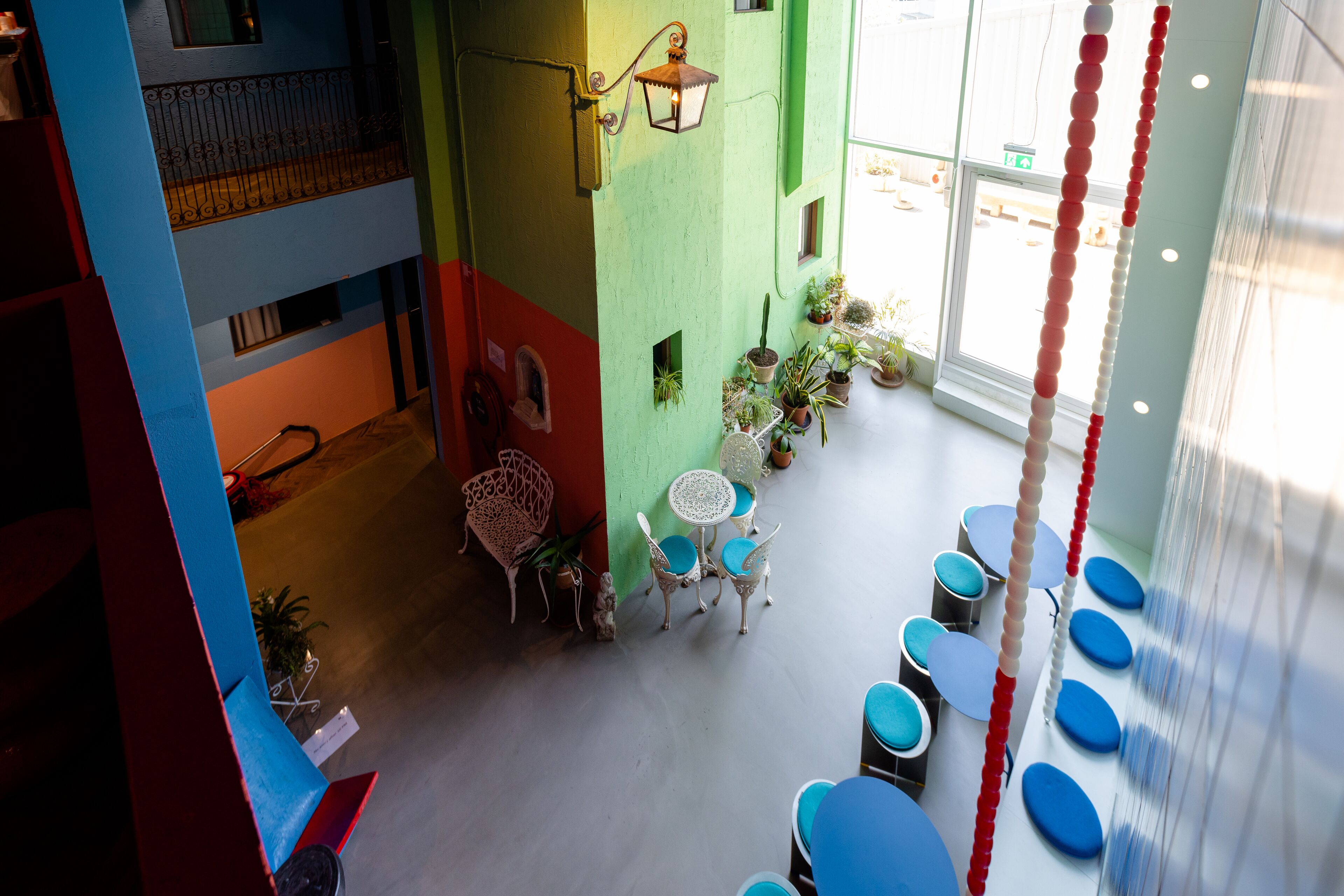 Interior em vários níveis com varanda, área de estar com cadeiras azuis e plantas em vasos.
