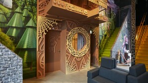 Een kamer met een uniek architectonisch ontwerp, waaronder een rond raam en een trap met een giraffepatroon.