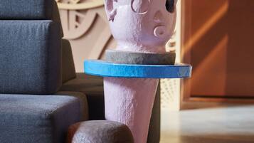 Een sculptuur toont een figuur bij een blauw platform, een stoel en een deur met decoratief ontwerp.
