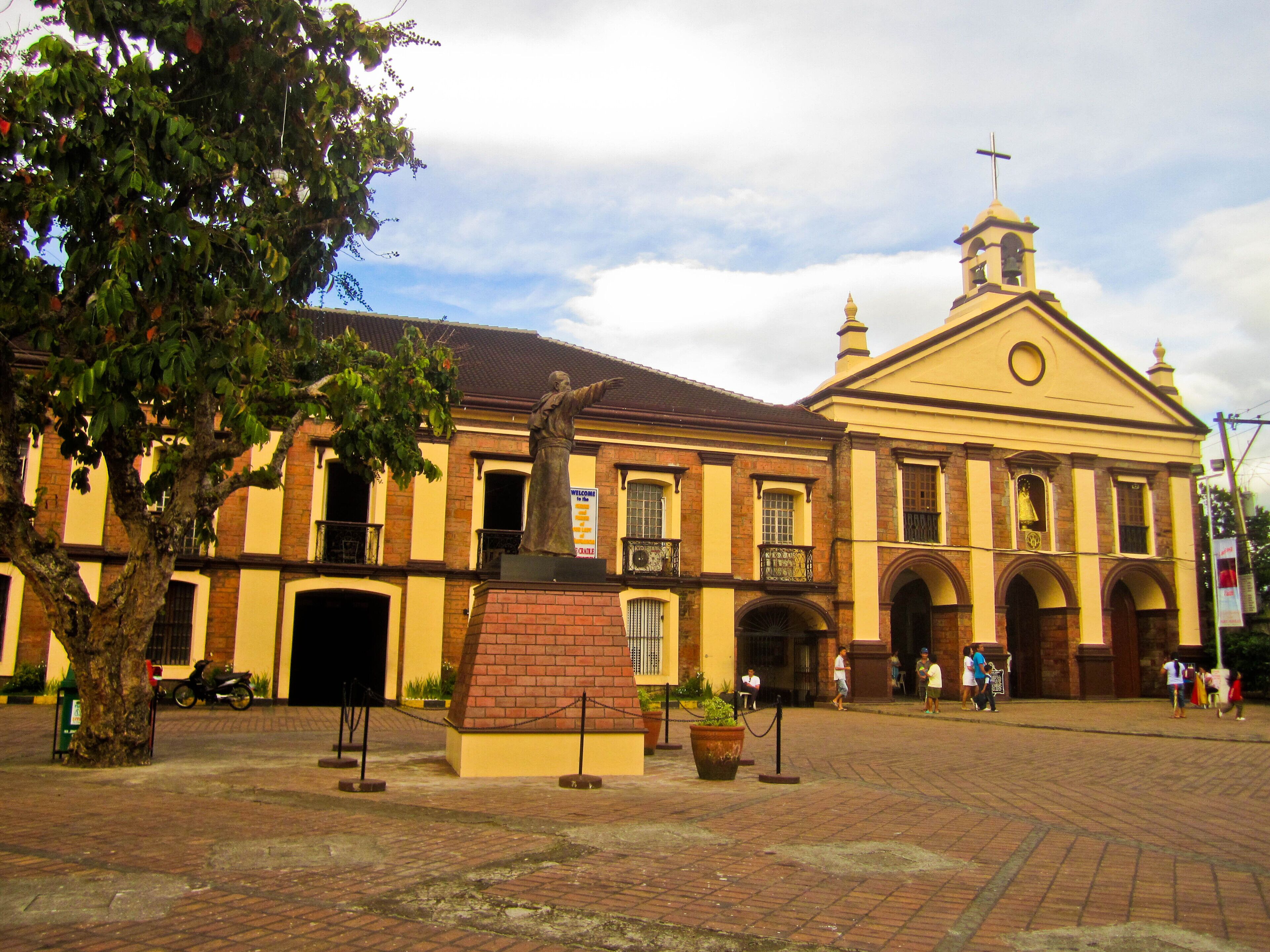 A historic building with a prominent bell tower and a statue in front.