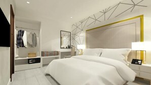 Una habitación de hotel moderna con una cama grande, una mesita de noche con lámpara, un armario y un espejo.